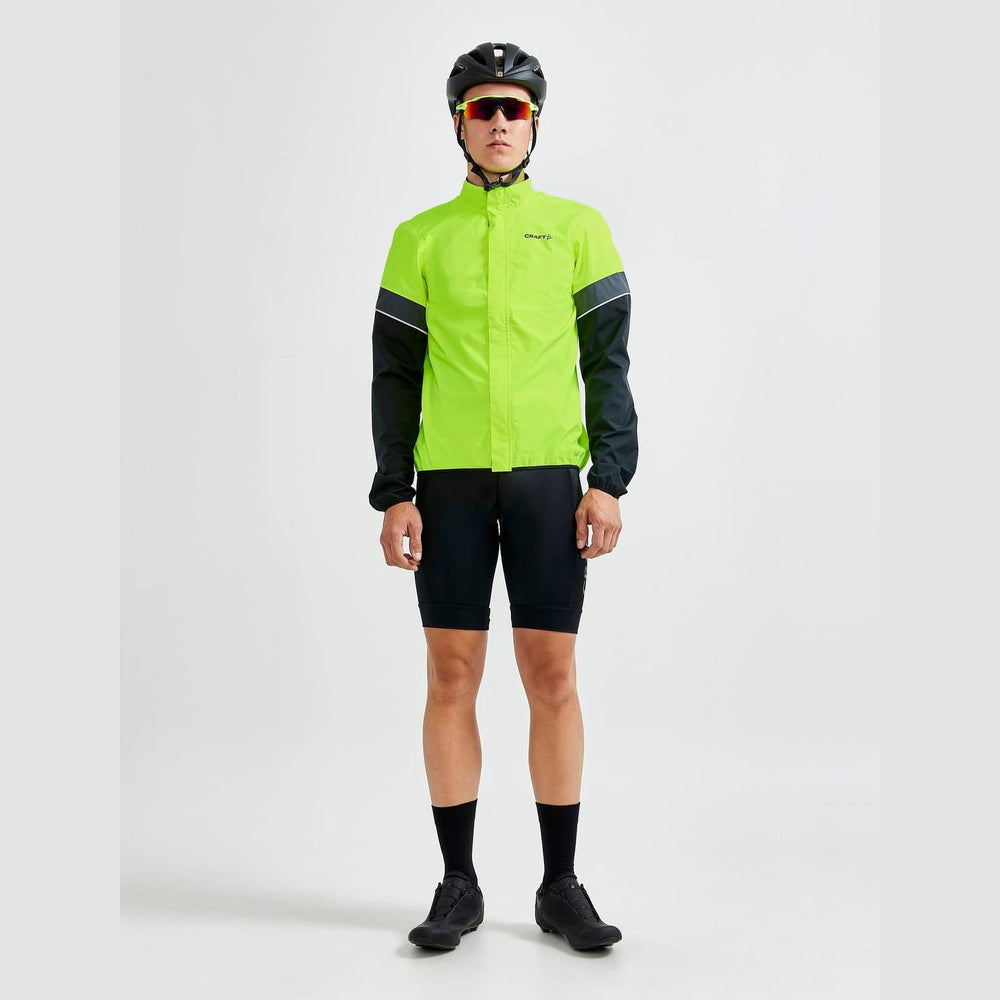 Person wearing a bright green cycling jacket and black shorts on a white background