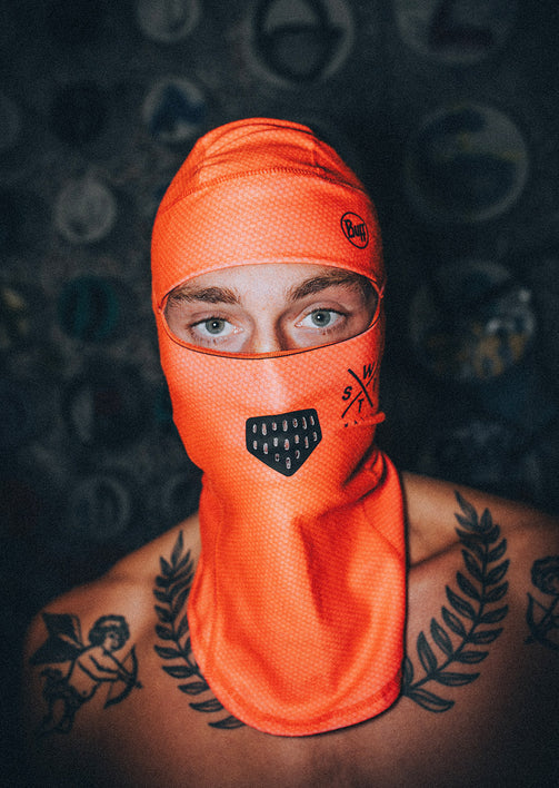 Person wearing an orange balaclava with a dark background