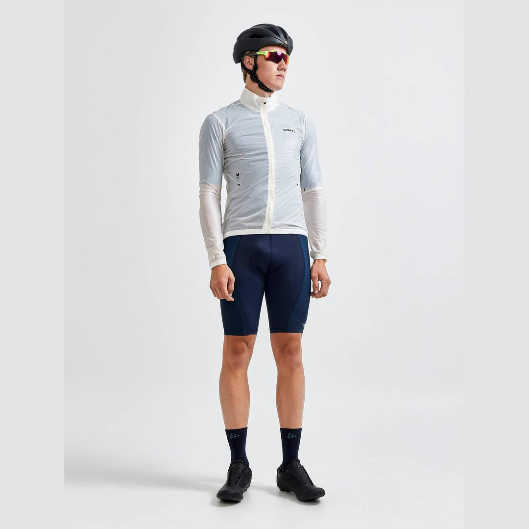 Cyclist wearing a light gray long-sleeve cycling jersey and navy shorts on a white background