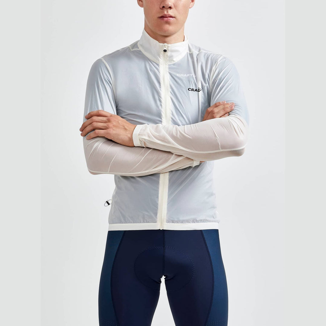 Person wearing a light gray cycling jacket with navy blue cycling pants on a white background