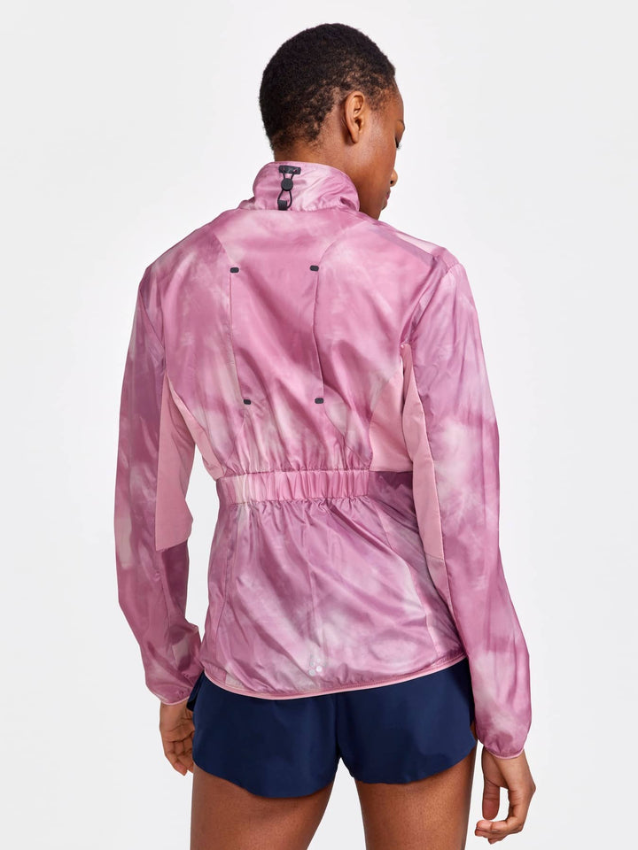 Person wearing a pink tie-dye jacket and navy shorts on a light gray background