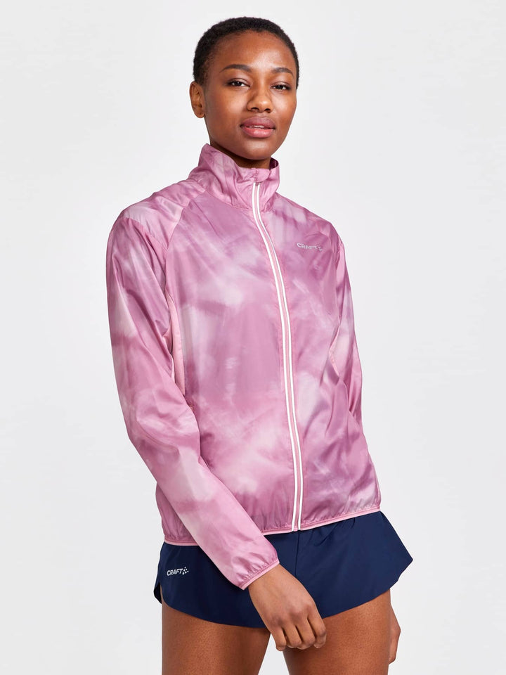 Person wearing a pink tie-dye jacket and navy shorts on a white background