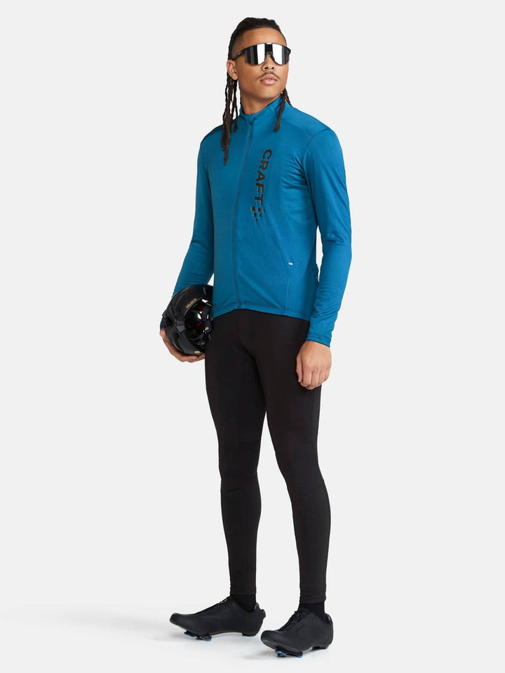 Person wearing a blue long-sleeve cycling jersey and black cycling pants on a white background