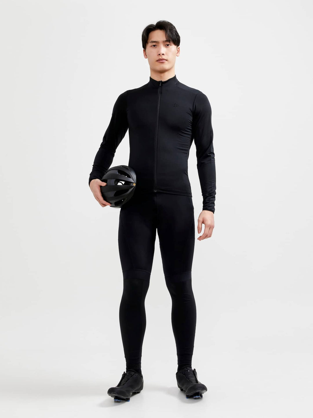 Person wearing a black full-body suit holding a helmet on a white background