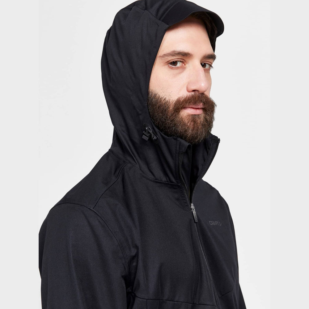 Man wearing a black hooded jacket on a light gray background