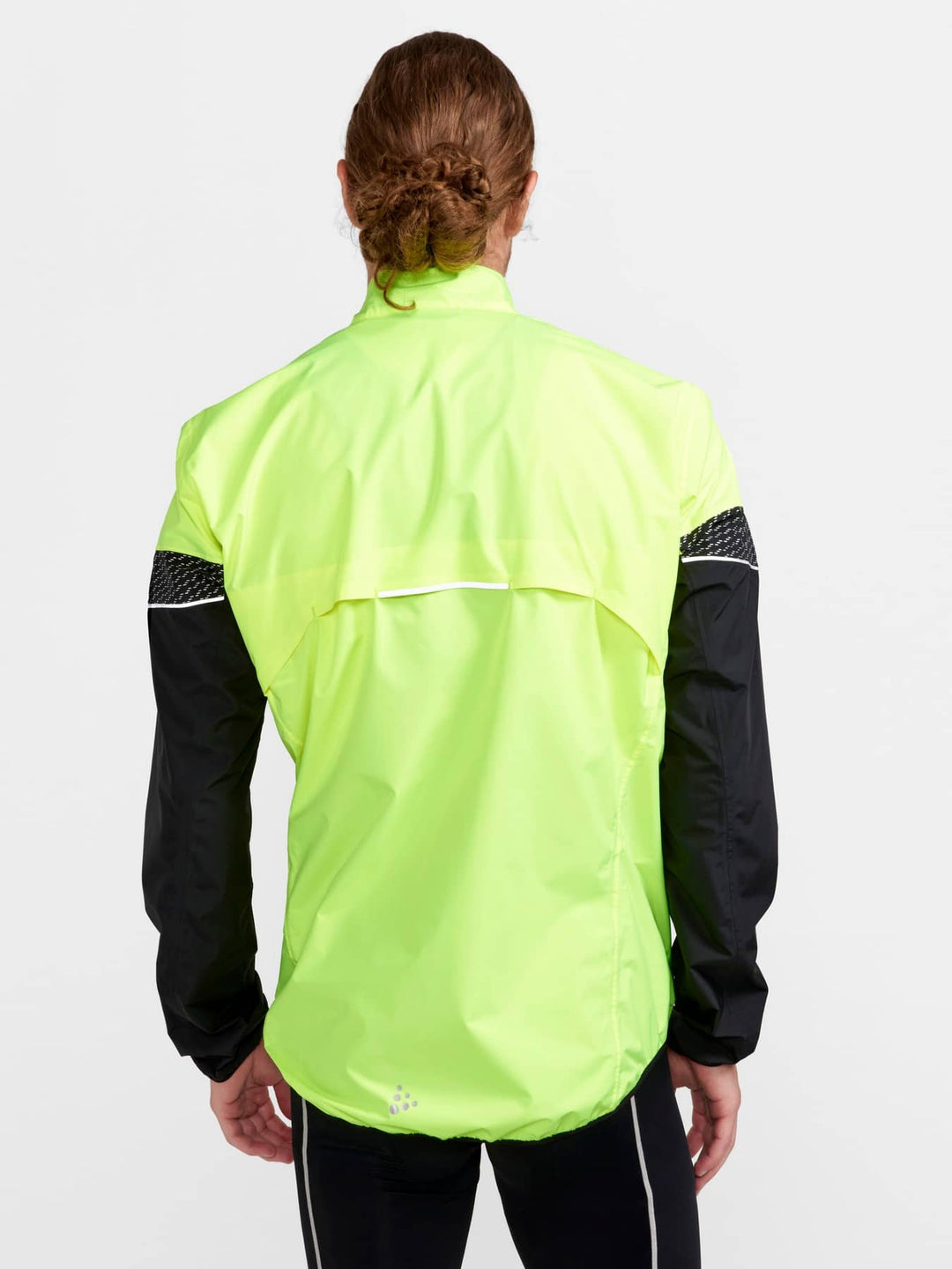 Person wearing a bright yellow running jacket with black sleeves on a white background