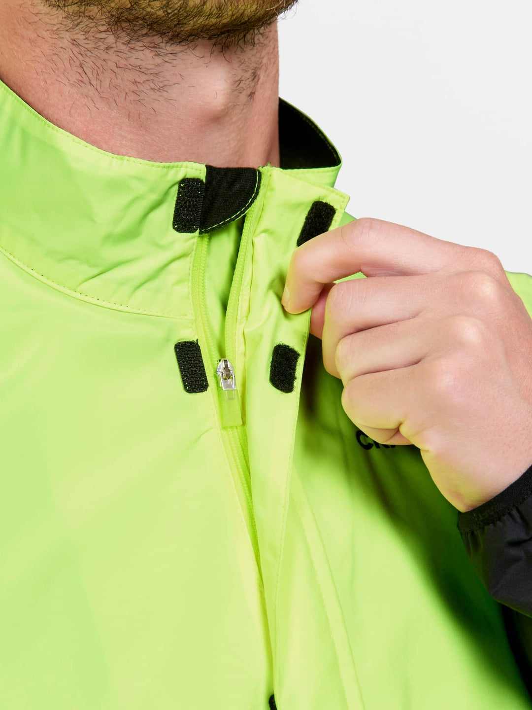 Person wearing a bright green jacket with a close-up of the zipper area.