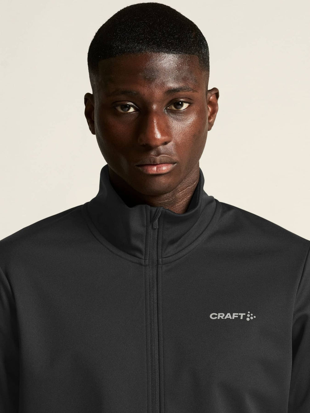 Man wearing a black jacket with Craft logo on a beige background