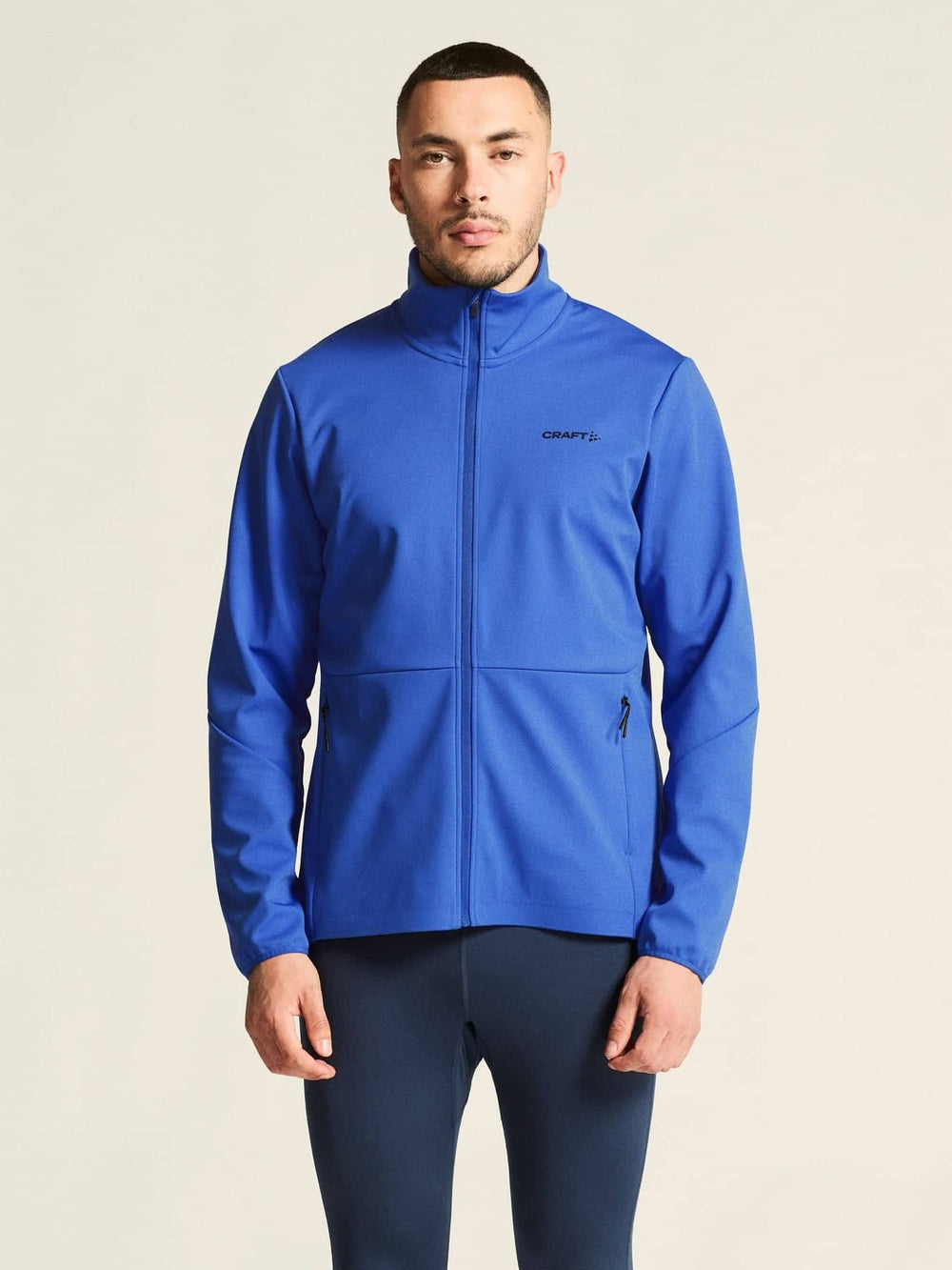 Man wearing a blue jacket with a visible brand logo on a beige background