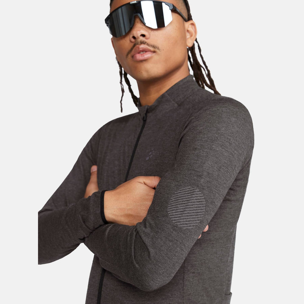 Man wearing a dark gray long-sleeve shirt with reflective sunglasses on a light gray background