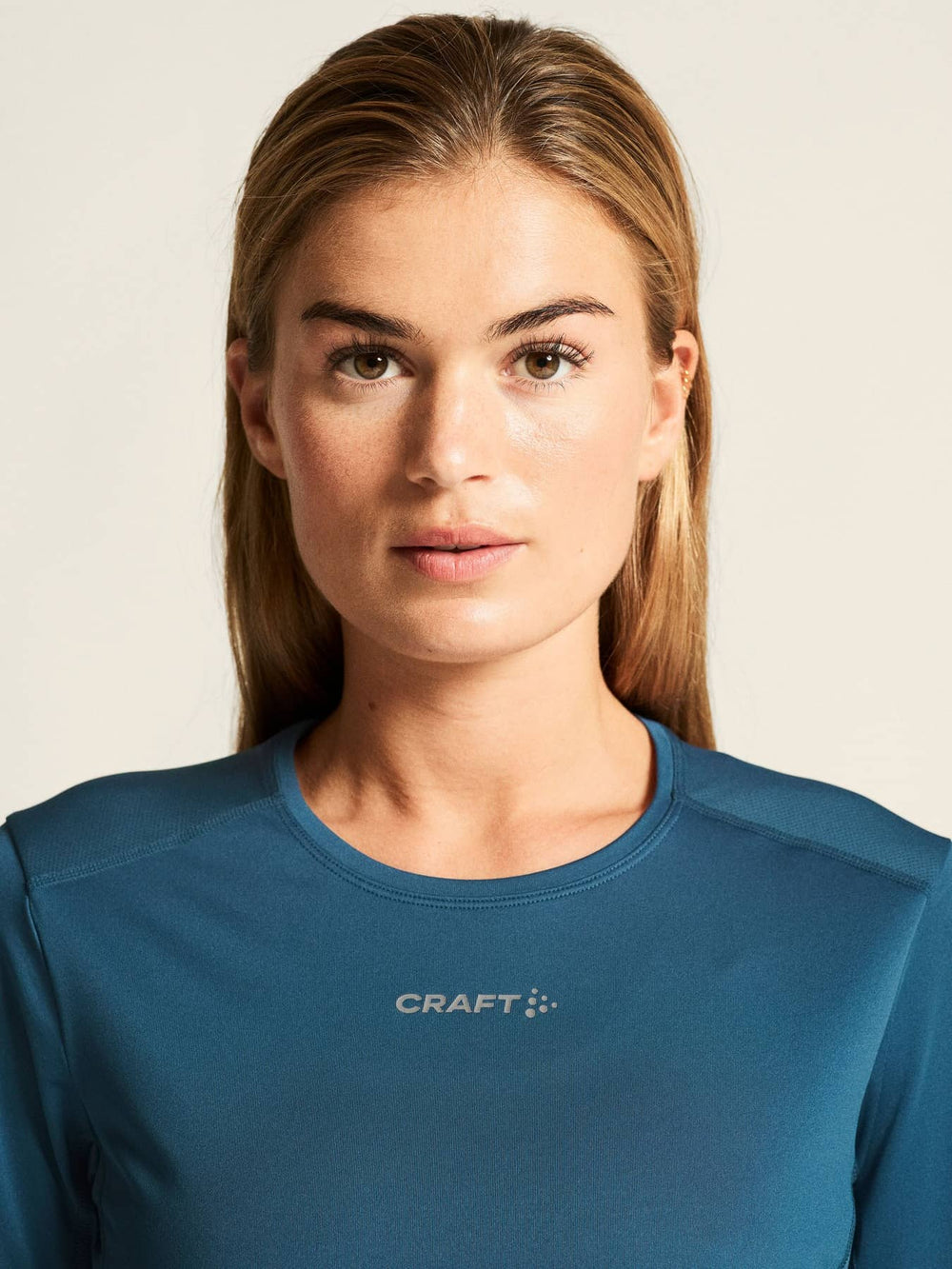 Woman wearing a blue Craft shirt against a plain background