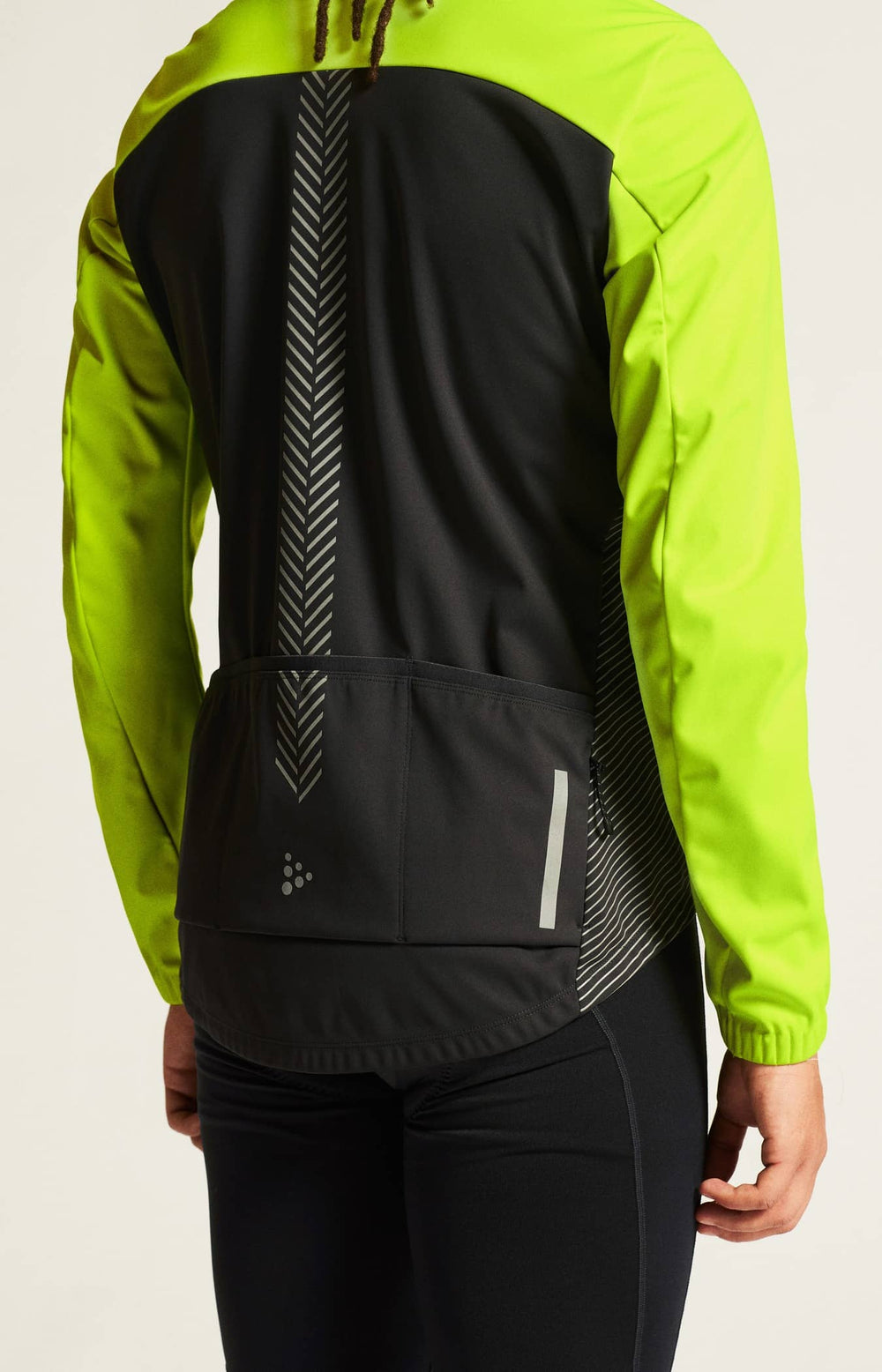 Person wearing a bright green jacket with a black back panel on a white background