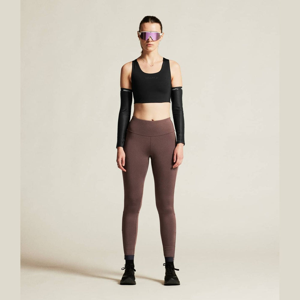 Person wearing a black sports bra and brown leggings on a beige background