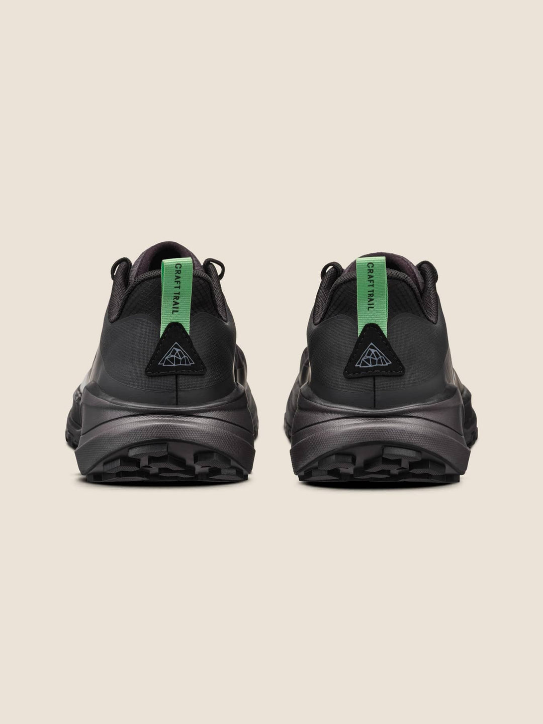 Black athletic shoes with green accents on a beige background
