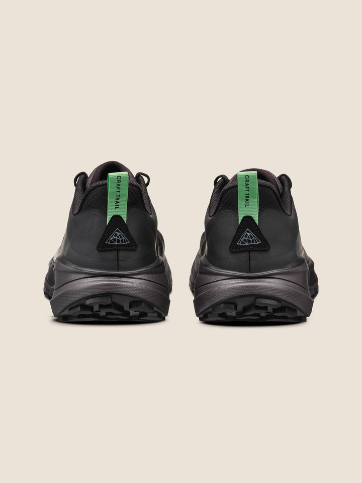 Black athletic shoes with green accents on a beige background