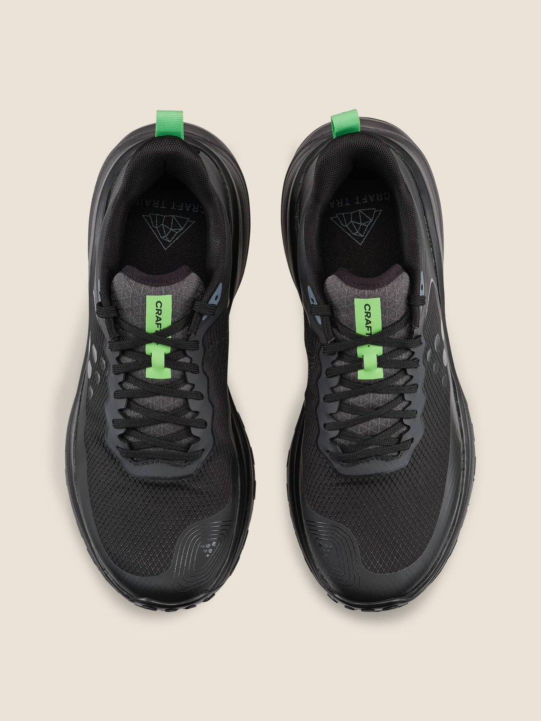 Black running shoes with green accents on a beige background