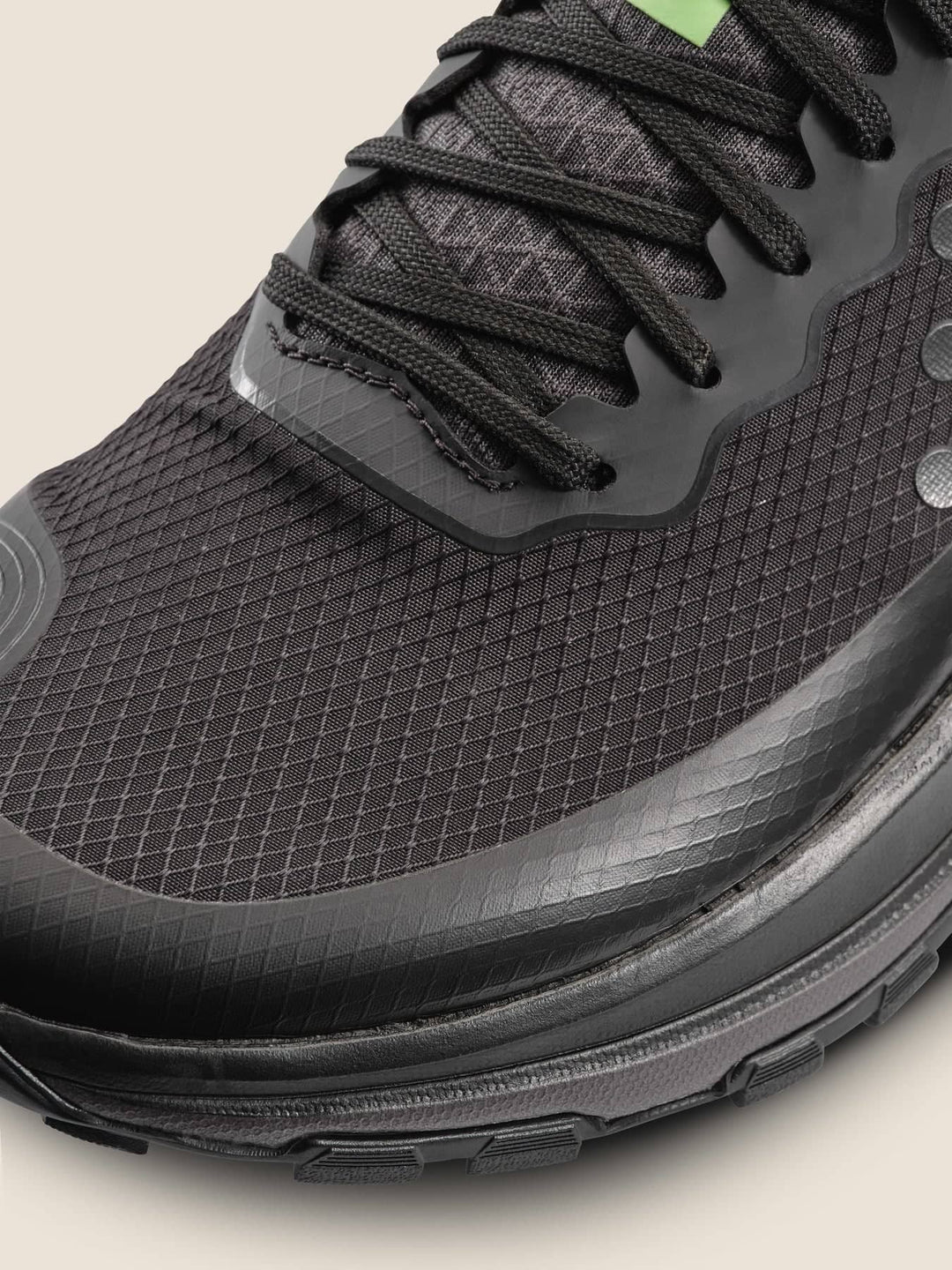 Close-up of a black athletic shoe with textured sole and laces on a light background