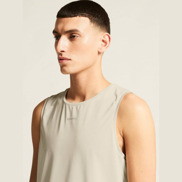 Man wearing a beige tank top against a neutral background