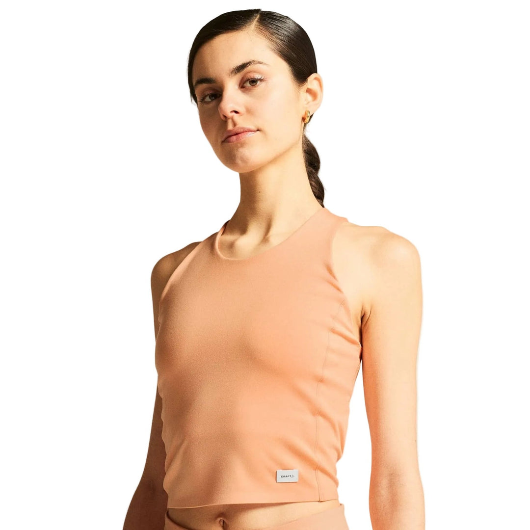 Female model wearing Craft Collective Cropped Singlet in Apricot, stylish cropped tank top designed for active and casual wear.
