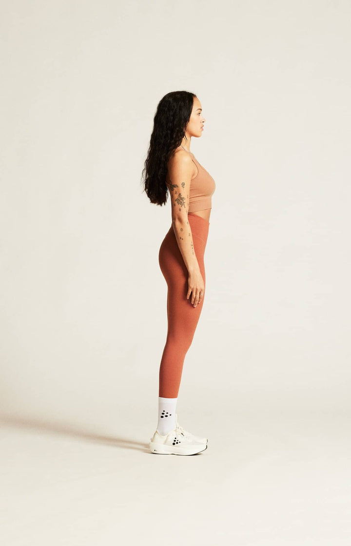 Woman in a brown outfit standing against a plain background