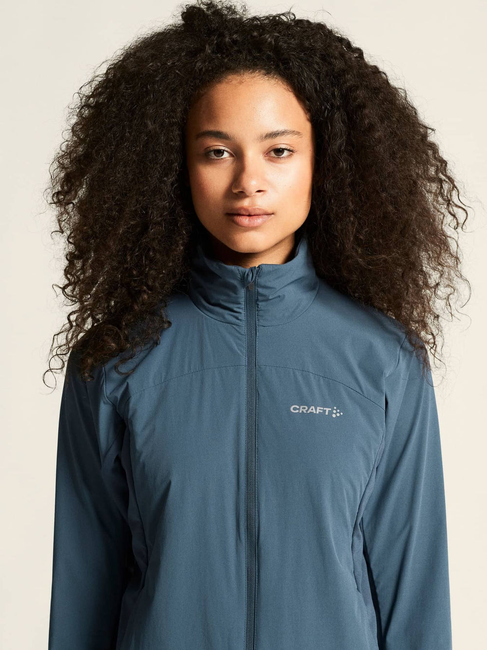 Person wearing a blue jacket with Craft logo on a beige background