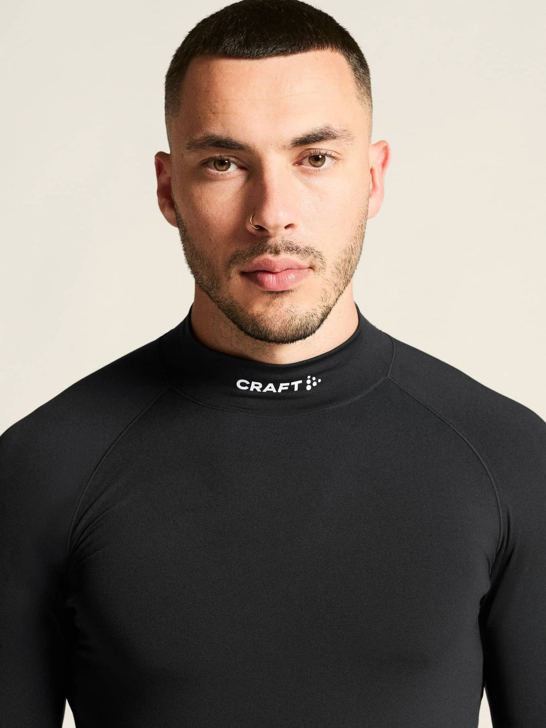 Man wearing a black Craft athletic shirt against a beige background