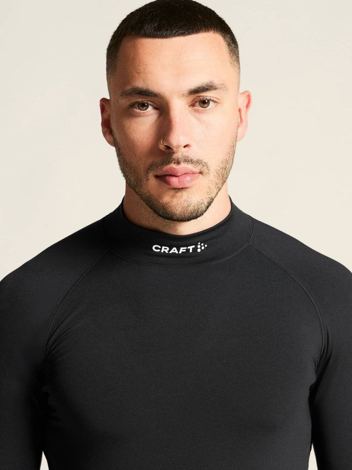 Man wearing a black Craft athletic shirt against a beige background