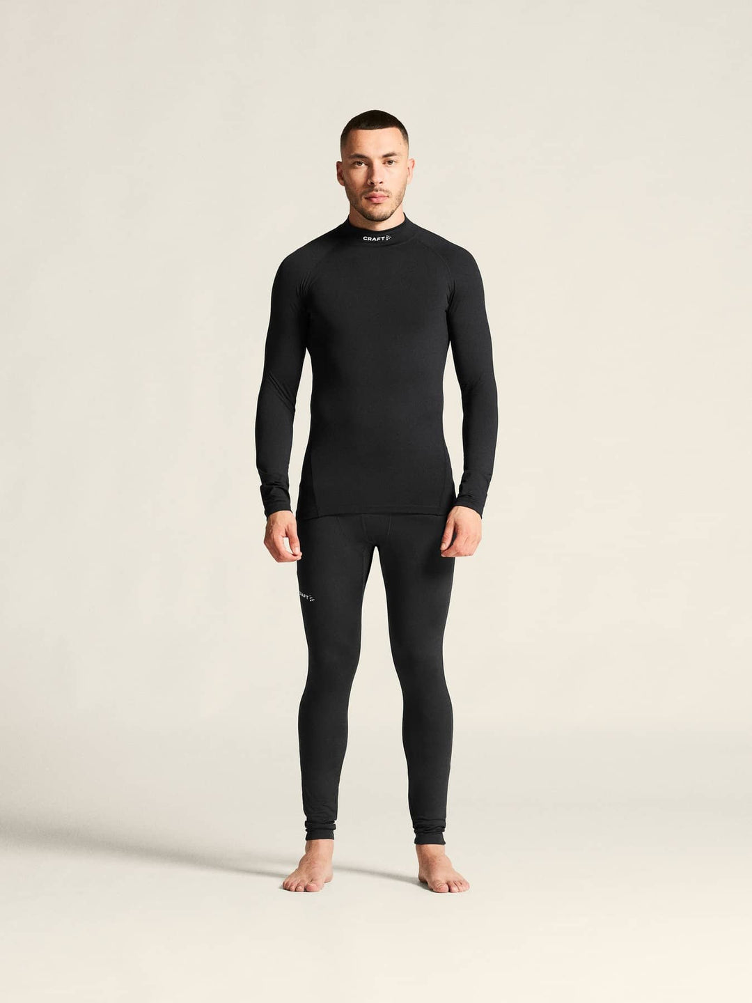 Man wearing a black long-sleeve shirt and pants on a beige background