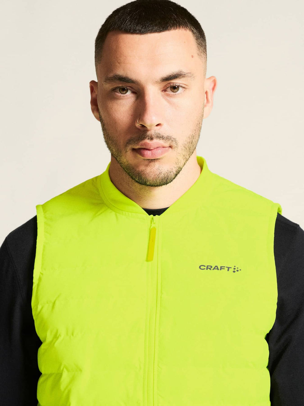 Man wearing a bright yellow vest with 'Craft' branding on a plain background