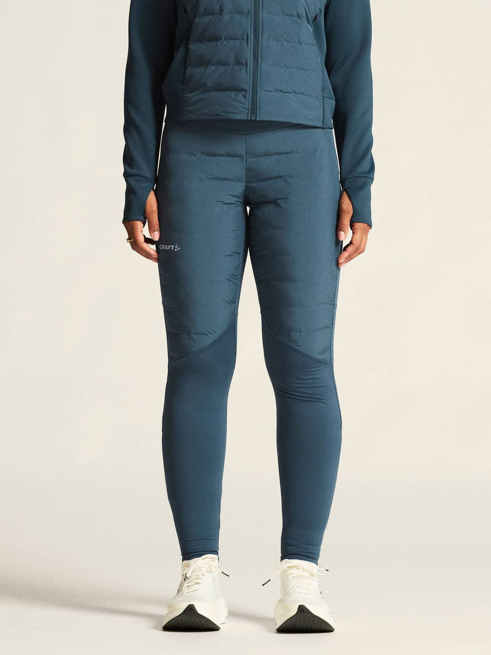 Person wearing a blue puffer jacket and leggings on a beige background