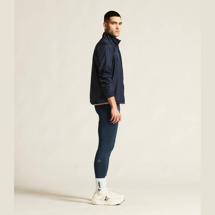 Man wearing a navy jacket and blue leggings on a beige background
