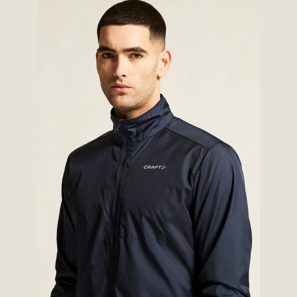 Man wearing a navy blue jacket with 'Craft' logo on a beige background