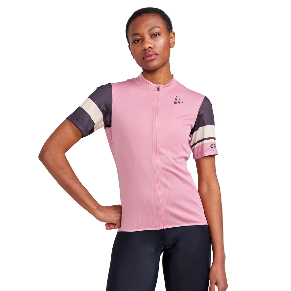 Pink women’s cycling jersey with black and cream sleeve stripes, made from lightweight recycled fabric, shown on a model.