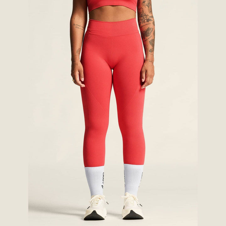 Person wearing red leggings and white sneakers on a plain background
