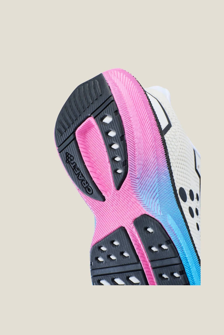 Close-up of a running shoe sole with pink, black, and blue design on a beige background