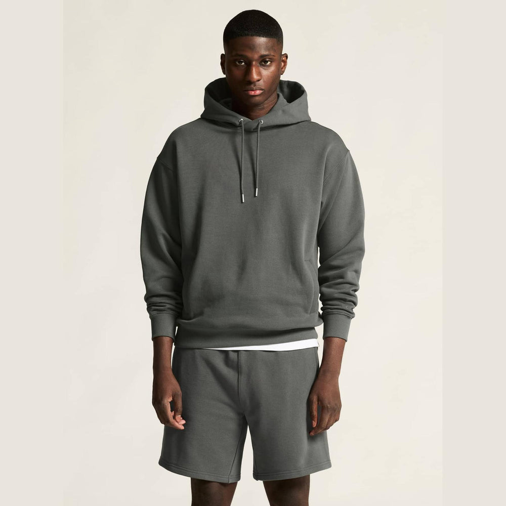 Man wearing a gray hoodie and shorts on a plain background