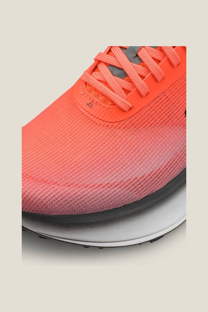 Close-up of a bright orange running shoe with a gradient design on a light beige background