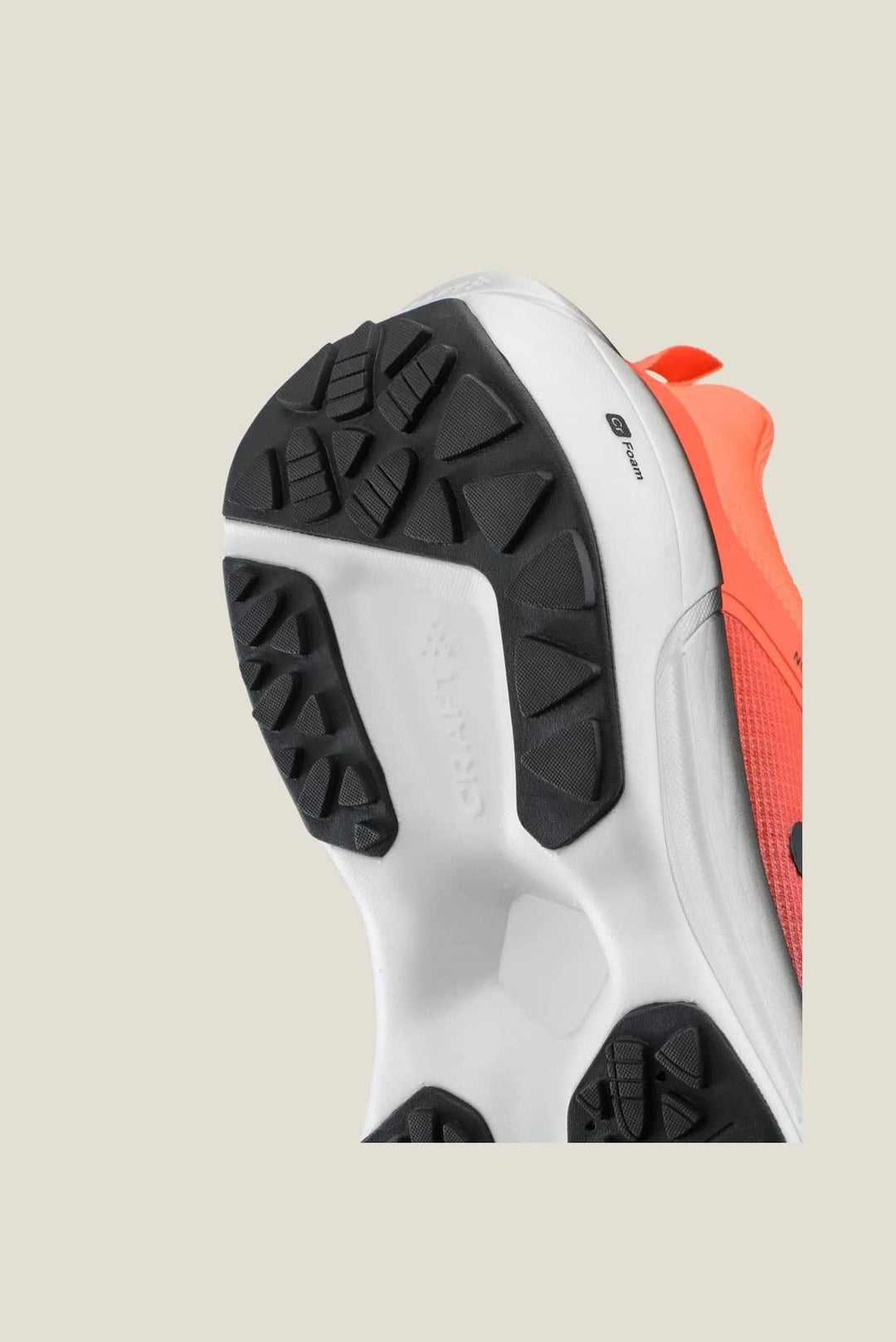 Close-up of a sneaker with white sole and black tread pattern on a beige background