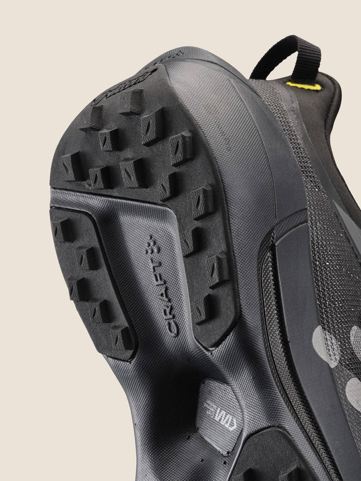 Close-up of a black hiking shoe with a textured sole on a beige background