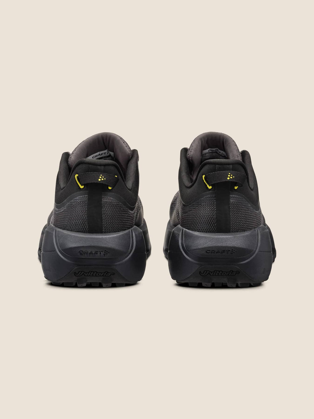 Black athletic shoes with yellow accents on a beige background