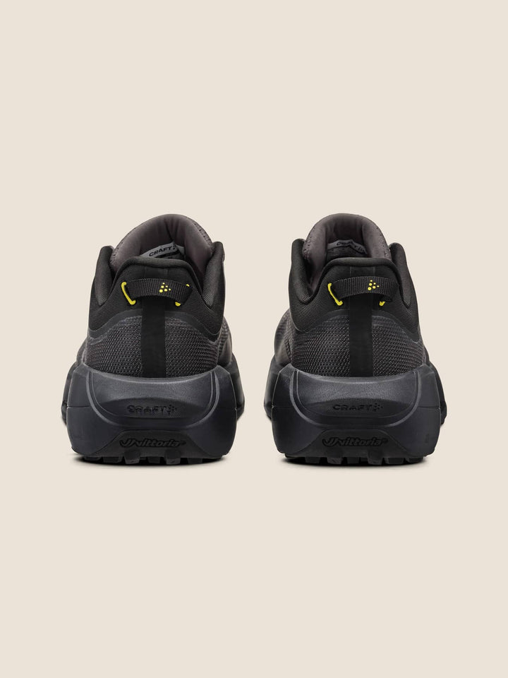 Black athletic shoes with yellow accents on a beige background
