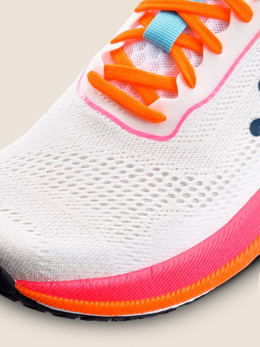 Close-up of a running shoe with orange laces and pink sole on a light background