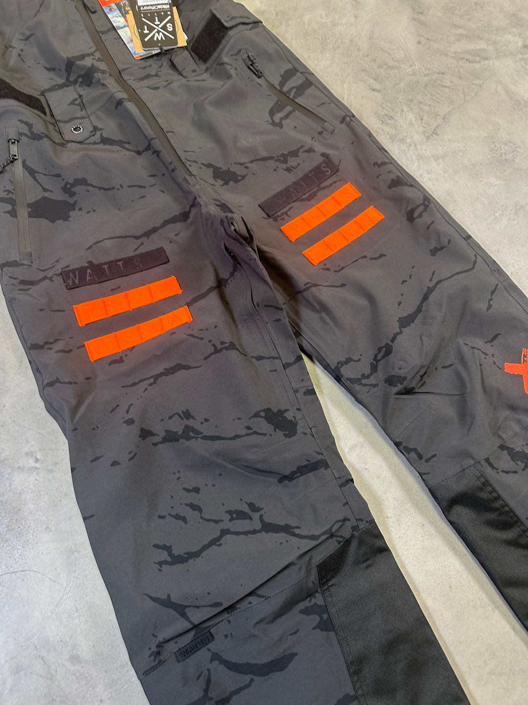 WATTS Cork Bib Pants with waterproof breathable fabric, adjustable bib straps, reinforced lower legs, and snow gaiters.