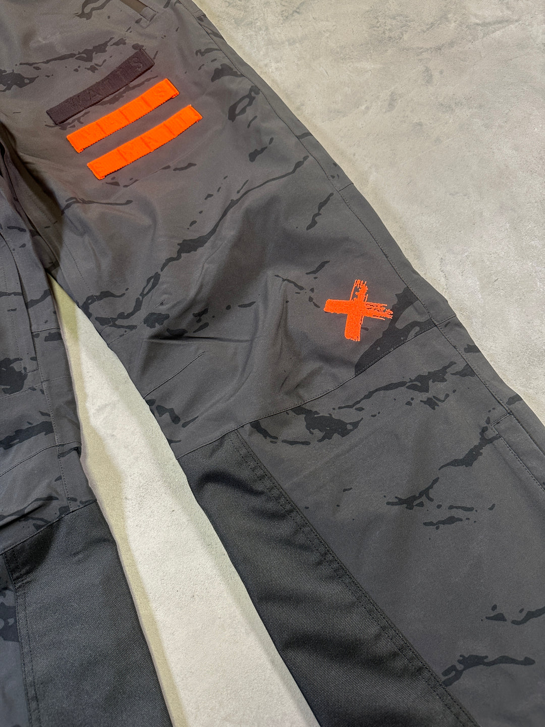 Gray tactical pants with orange markings on a concrete surface