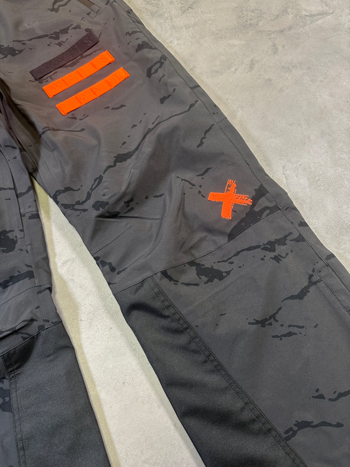 Gray tactical pants with orange markings on a concrete surface