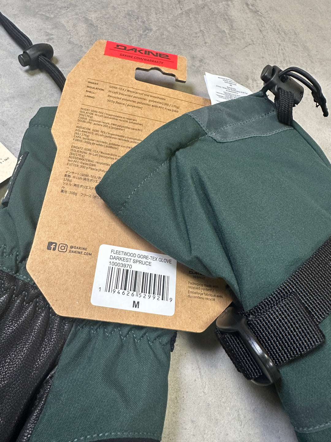 Green jacket with a brand tag and label on a gray surface