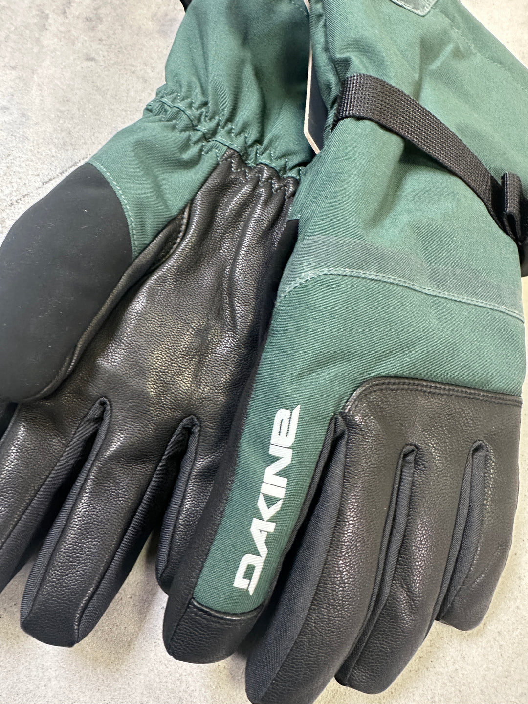 Pair of green and black gloves with Dakine branding on a light background