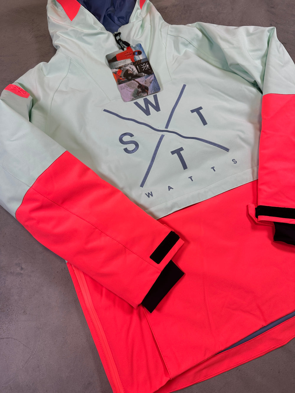 Red and gray jacket with 'STMS' branding on a gray surface