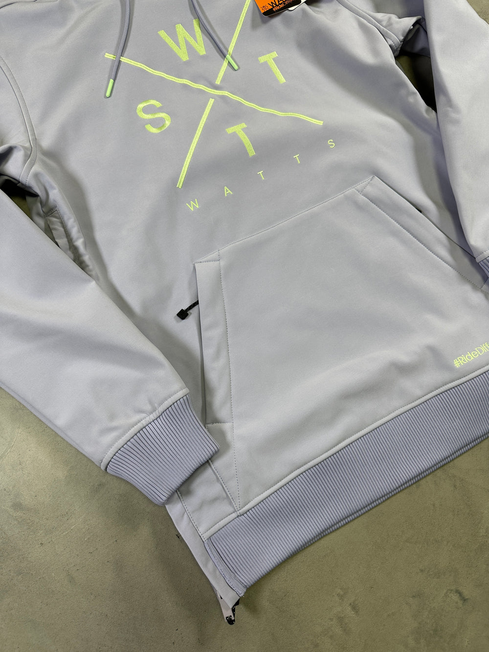 Gray jacket with neon green text on a beige surface