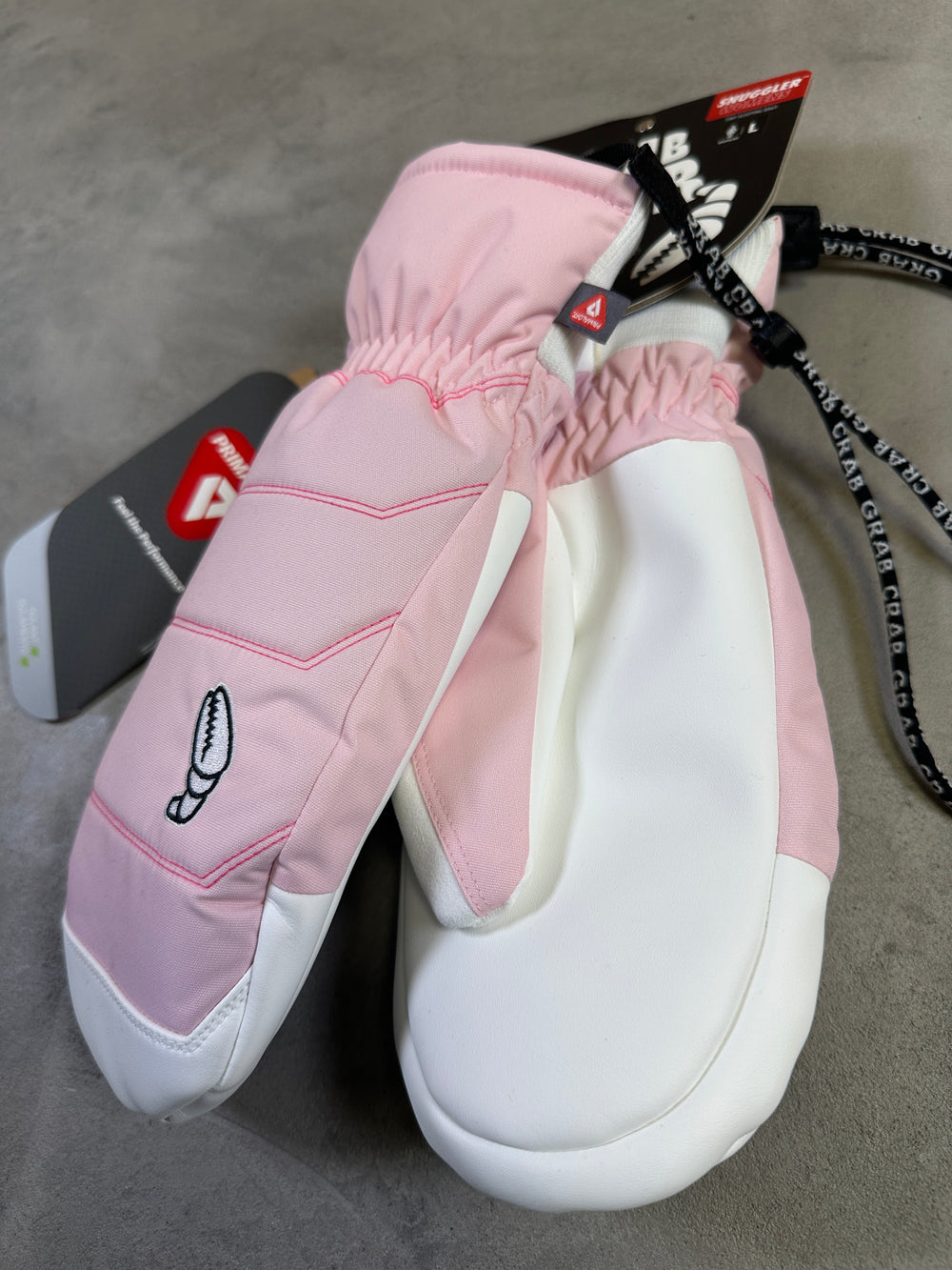 Pink and white mittens with a fish design on a gray surface